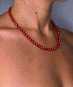 collier en pierres de jaspe rouge porté à même la peau