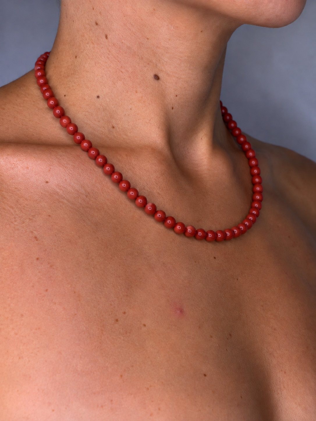 collier en pierres de jaspe rouge porté à même la peau